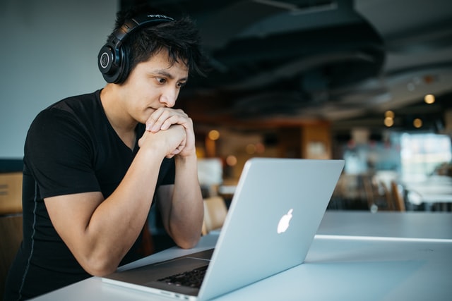 Young man viewing laptop and wearing headset